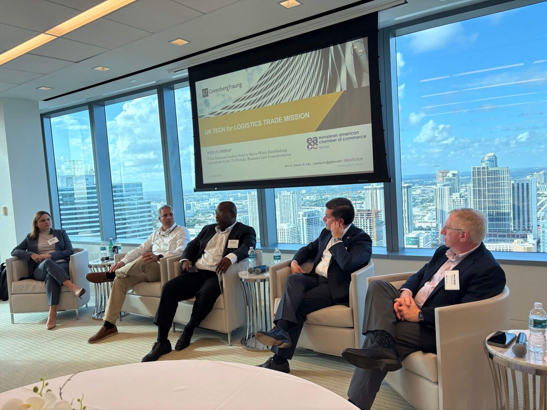 A group of people are sitting in chairs in front of a large screen.